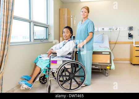 Patient sur fauteuil tout en se tenant derrière la fenêtre à l'infirmière Banque D'Images