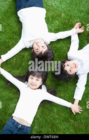 Trois enfants allongés sur l'herbe Banque D'Images