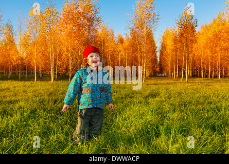 Trois ans rire petit garçon debout sur la pelouse du parc à l'automne Banque D'Images