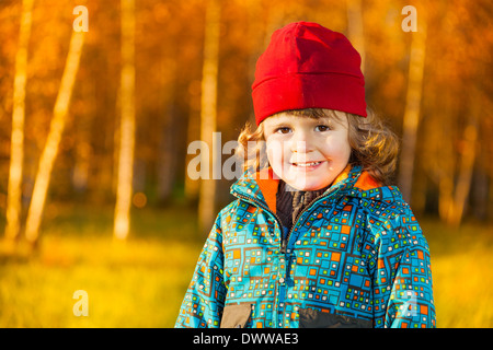 Fermer portrait of happy smiling trois ans petit garçon debout sur la pelouse du parc à l'automne Banque D'Images