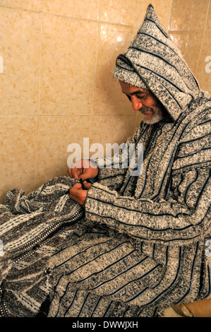 Couture à la main sur mesure marocain une djellaba traditionnelle berbère dans son atelier, Marrakech, Maroc Banque D'Images