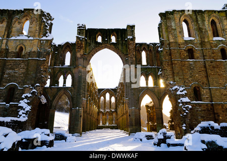 La lumière du soleil qui brillait à travers les fenêtres dans les ruines de l'abbaye de Rievaulx sous une couverture de neige sur un jour d'hiver lumineux Banque D'Images