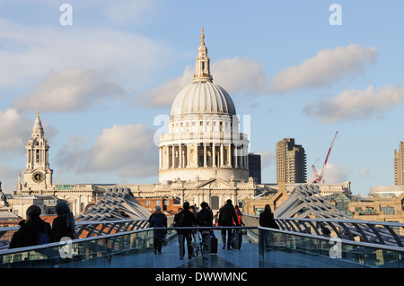 Les gens de marcher à travers Millenium Bridge sur la Tamise à Londres avec la Cathédrale St Paul à l'arrière-plan. Banque D'Images