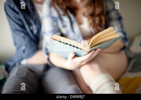 USA, Massachusetts, Mid section of young woman reading on bed Banque D'Images