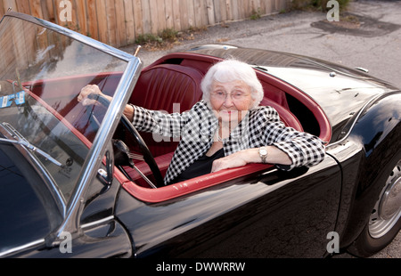 Femme âgée derrière la roue de voiture de sport classique Banque D'Images