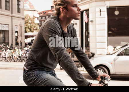 Vue latérale du jeune homme à vélo on city street Banque D'Images