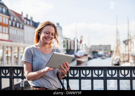 Happy woman using digital tablet against railing at harbor Banque D'Images