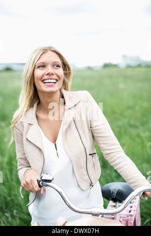 Happy young woman with bicycle à la route tout en se tenant sur le terrain Banque D'Images