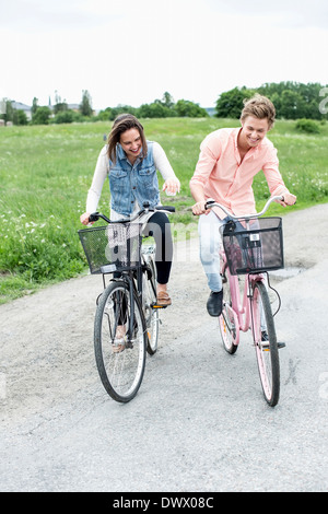 Happy friends riding bicycles on country road Banque D'Images