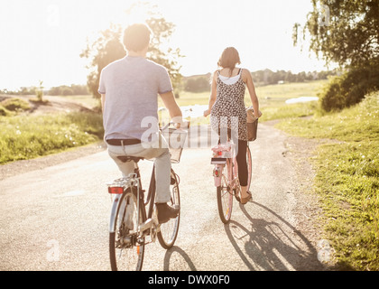 Vue arrière de jeunes amis riding bicycles on country road Banque D'Images