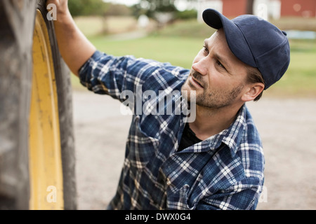Young farmer la réparation de la roue du tracteur à la ferme Banque D'Images