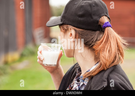 Vue de côté femme boire du lait à la ferme Banque D'Images