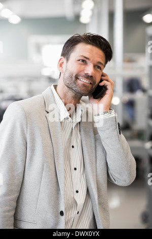 Smiling businessman answering mobile phone in manufacturing plant Banque D'Images