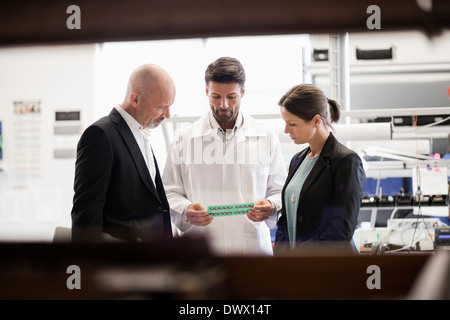 Engineer discussing machine avec des gens d'affaires en usine Banque D'Images