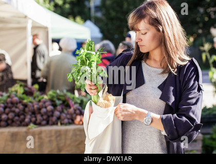 Jeune femme d'acheter les légumes feuilles at market Banque D'Images