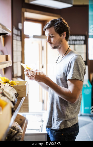 Young man reading label in grocery store Banque D'Images