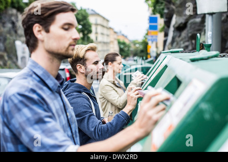 Les amis de mettre matières recyclables dans les bacs de recyclage Banque D'Images