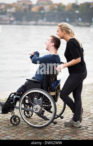 Heureux homme handicapé avec gardien enjoying view by lake Banque D'Images