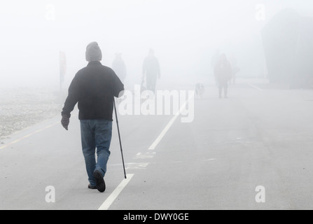 Les gens qui marchent le long d'une promenade dans le brouillard. Banque D'Images