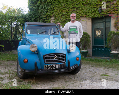 Un fier propriétaire de 2CV Citroën à côté de sa voiture Banque D'Images