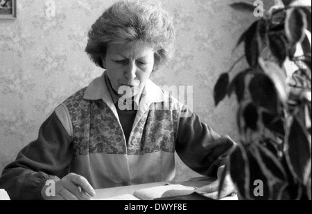 Berlin, RDA, femme assise à un bureau en feuilletant un journal intime Banque D'Images