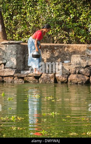 Le Sud de l'Inde du Sud Kerala backwater croisière canal navigable jusqu'à laver les plats pots en métal dans l'eau par étapes escaliers Banque D'Images