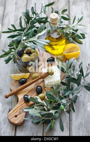 Olives vertes et noires avec une bouteille d'huile d'olive sur la plaque en bois d'olivier avec fourche d'olive grecque traditionnelle Banque D'Images
