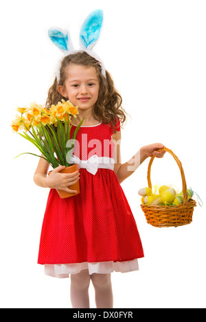 Belle fille en robe rouge avec des oreilles de lapin holding panier avec des œufs de Pâques et les jonquilles fleurs isolé sur fond blanc Banque D'Images