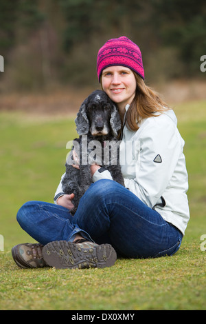 Un vieux chien Cocker assis dehors sur l'herbe dans la campagne avec son propriétaire Banque D'Images