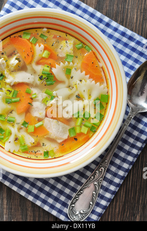 Soupe de poulet avec des pâtes farfalle dans le bol sur la table en bois Banque D'Images