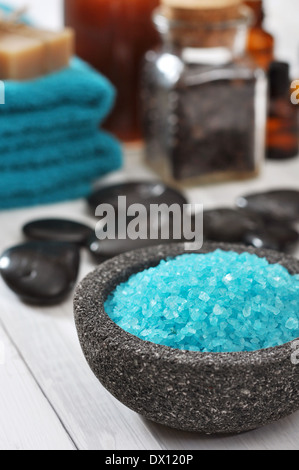 Spa composition with blue sea salt and massaging stones on white wooden background Banque D'Images