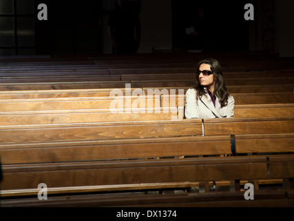 Femme en prière dans l'église et de l'air présence invisible à sa droite. Banque D'Images