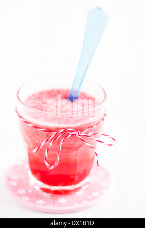 Smoothie aux fraises de gros plan et cuillère en plastique bleu sur la plaque en verre rose Banque D'Images