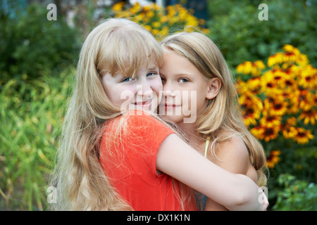 Sisters hugging in garden Banque D'Images