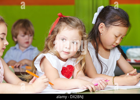 Différents enfants dessin avec crayons et livre à colorier dans un jardin Banque D'Images