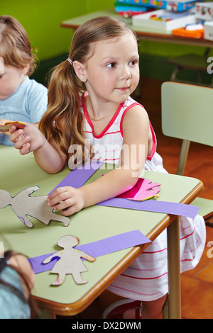 Les enfants dans un groupe à la table faisant l'art et de l'artisanat à la maternelle Banque D'Images