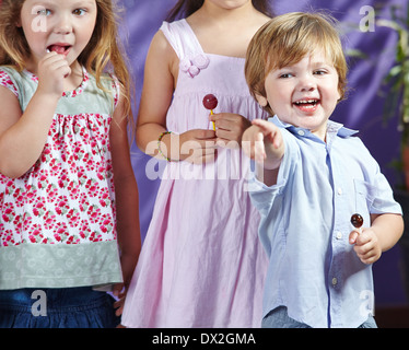 Happy boy with lollipop pointant avec le doigt dans un jardin Banque D'Images