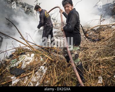 Phraeksa, Samut Prakan, Thaïlande. Mar 17, 2014. Les pompiers tentent d'éteindre un feu brûlant dans une décharge à Samut Prakan province environ 40 kilomètres de Bangkok. La décharge est construite sur un marais et les pompiers et les bénévoles luttant contre l'incendie ont été tomber par la végétation emmêlée dans le marais en dessous. Apparemment, un incendie dans la décharge a commencé spontanément à Edmonton au cours du week-end et menace les foyers de travailleurs qui vivent près de la décharge. Credit : ZUMA Press, Inc./Alamy Live News Banque D'Images