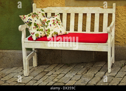 Banc en bois rustique romantique en plein air avec des oreillers contre mur jaune Banque D'Images