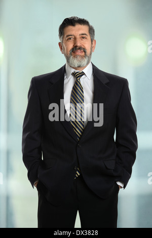 Portrait of Hispanic senior businessman with hands in pockets inside office building Banque D'Images