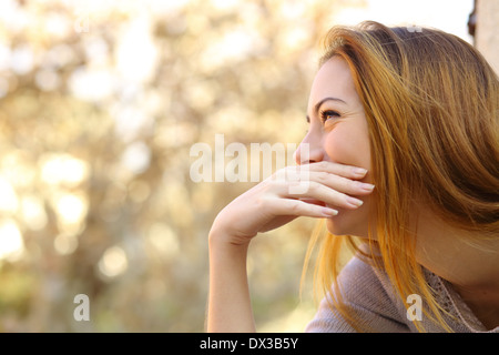 Happy woman laughing couvrant sa bouche avec une main avec un fond chaleur Banque D'Images