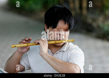Un musicien aveugle joue une flûte de bambou à l'entrée du temple Ngoc Son, Hanoi, Vietnam, Asie du sud-est Banque D'Images