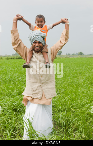 Agriculteur indien portant son fils dans les exploitations agricoles Banque D'Images