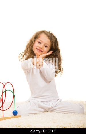 Happy little girls giving thumbs et assis sur un tapis isolé sur fond blanc Banque D'Images