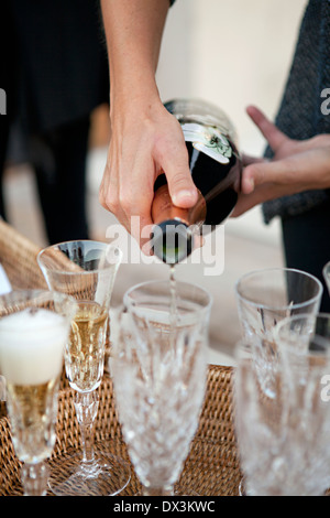Woman pouring champagne de bouteille dans des flûtes à champagne en cristal sur le bac, Close up Banque D'Images