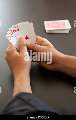 Vue de la quinte flush royale avec des coeurs dans les mains de l'homme jouant au poker avec des cartes à jouer, high angle view Banque D'Images