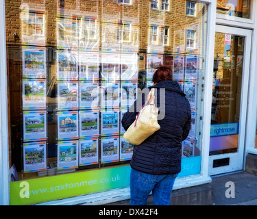 Une femme d'âge moyen à la recherche dans une fenêtre d'agents immobiliers Bakewell Derbyshire, Angleterre, Royaume-Uni Banque D'Images