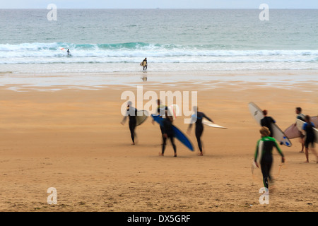 Groupe de surfeurs dans le motion blur walking on beach at sunset Banque D'Images
