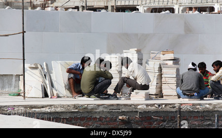 Travailler pour faire du carrelage en marbre à l'intérieur du site de construction le Temple d'or à Amritsar, en leur donnant la forme requise Banque D'Images