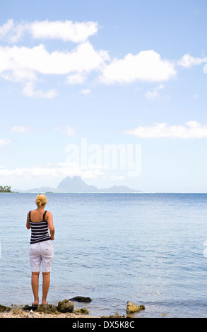 Femme sur la plage escarpée à l'océan au seascape view de Bora Bora Tahiti de Taha'a Banque D'Images